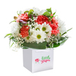 Full of life and optimism, this bouquet epitomises the cheerful character of Longford, as if the colours and scents of a summer day have been gathered and presented in a single, stunning gift. Arranged in a clean white square bag with practical ribbon handles, the display bursts forth with lush coral and deep red carnations-each petal densely ruffled and softly radiant-paired harmoniously with radiant white daisies and their shining yellow-green hearts. Wisps of cloud-like baby's breath float throughout, bestowing airy innocence to the ensemble. Just at the edge, a few tight purple-tinged buds add an element of surprise and promise, while enveloping, glossy leaves support the blooms like a protective cloak. The composition is expertly rounded and balanced, offering a tactile richness you'd expect from a seasoned Longford florist. Flooded with gentle, natural light, the image captures nuances of colour and freshness, echoing the simple joys of a neighbourly visit or spontaneous celebration-a bouquet meant to light up birthdays or anniversaries across Longford and beyond.